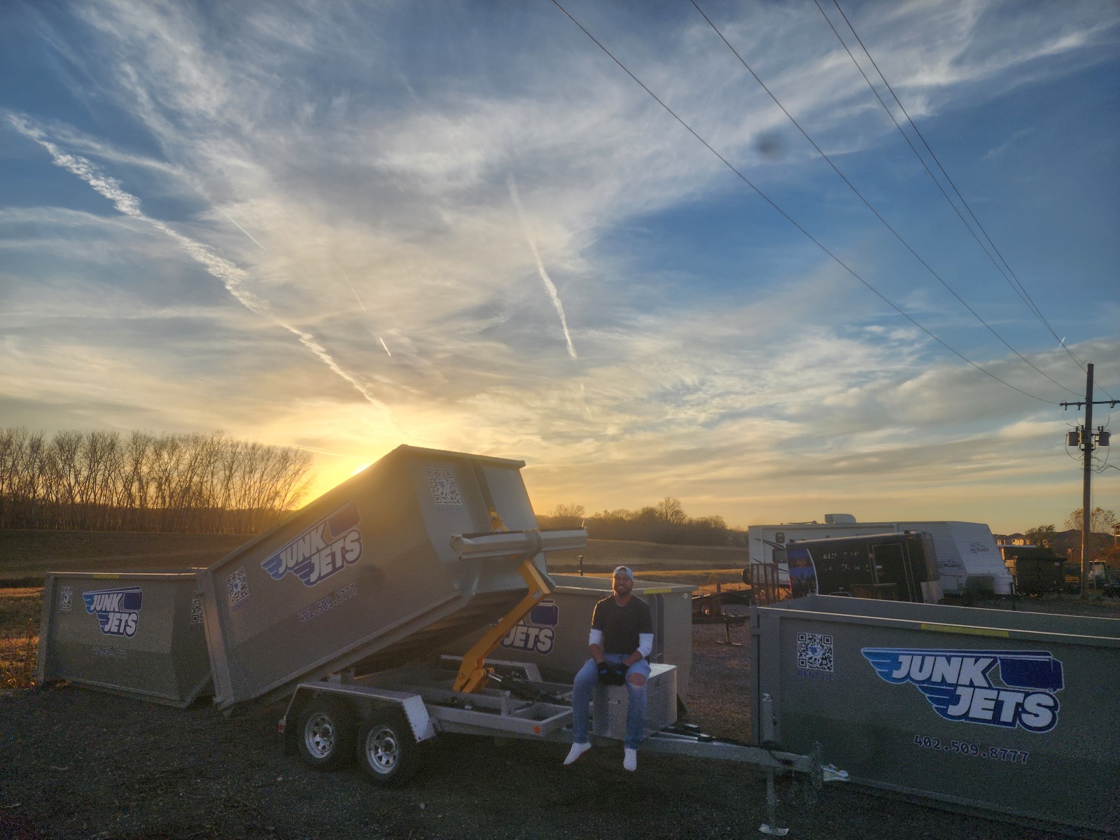 JunkJets truck delivering a dumpster at sunset